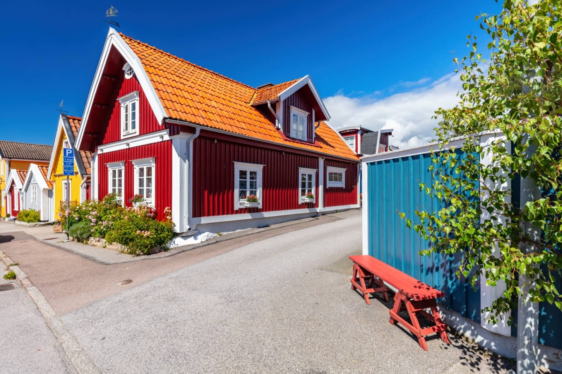 I en drömsk skärgårdsmiljö finner man ett rött trähus med traditionella vita knutar och ett tak i orange tegel